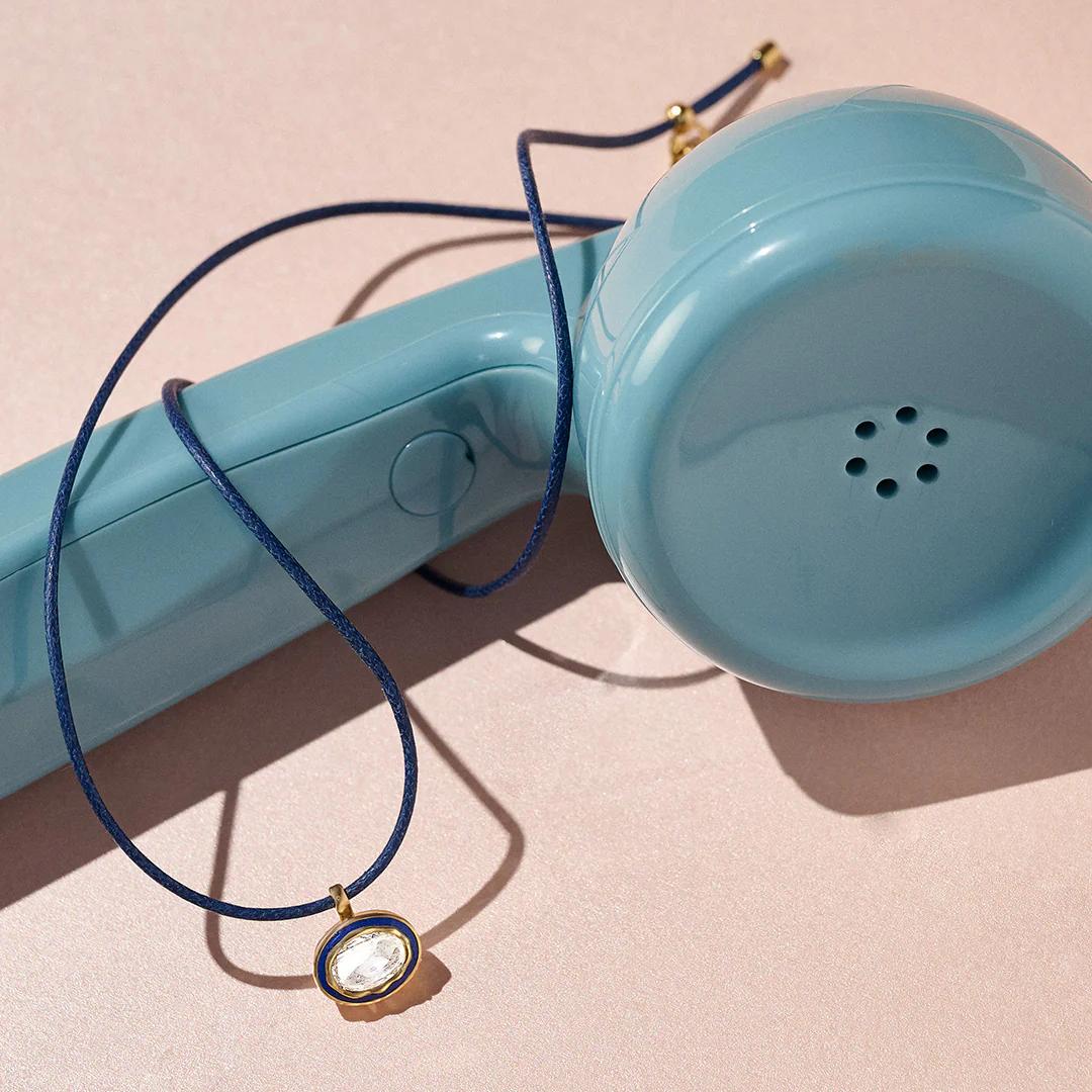 A lab-grown polki pendant photographed up close beside a vintage phone